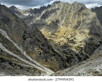 Dramatic sunlight illuminating a deep rocky alpine valley and mountain tarn in the High Tatras national park, Slovakia. View from Predne Solisko in Tatras mountains 