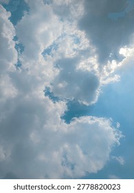 Dramatic sunlight peeking through heavy white clouds in a bright blue sky.
Ethereal skyscape with sun rays breaking through fluffy cumulus cloud formations.