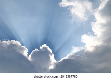 Dramatic sunrays, blue sky, grey and white clouds