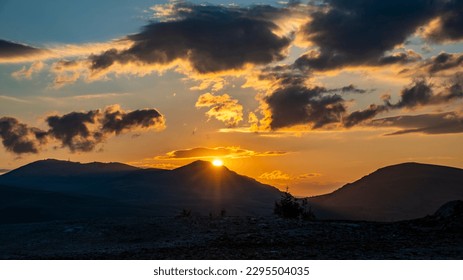 Dramatic Sunrise and Sunset with clouds on the sky over mountain range.