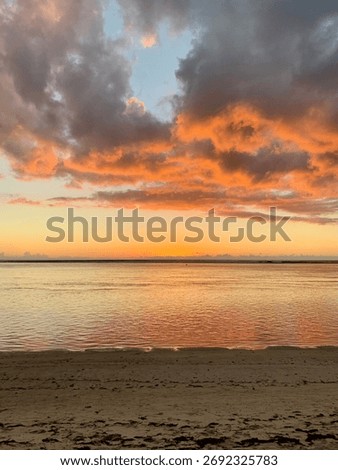 Dramatic Sunset At The Beach With Orange Sky And Still Water