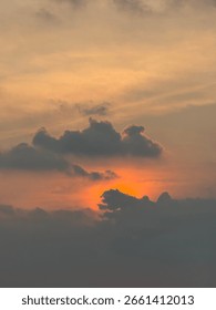 Dramatic Sunset Behind Silhouetted Clouds in Golden Sky