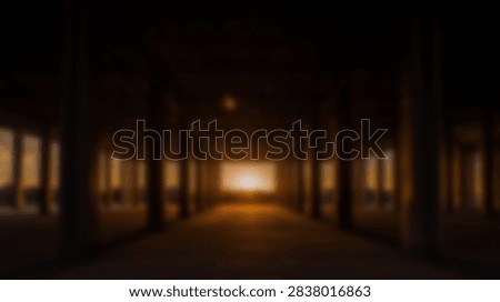 A dramatic sunset casts a warm golden light down a long, dark corridor lined with pillars, creating a sense of depth and mystery.