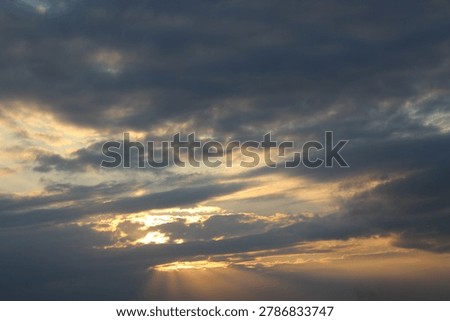 Dramatic sunset clouds with glowing sun rays in sky creating atmospheric skyscape with soft light and expressive natural texture