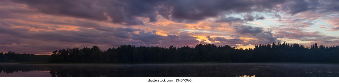 dramatic sunset with clouds over the forest lake