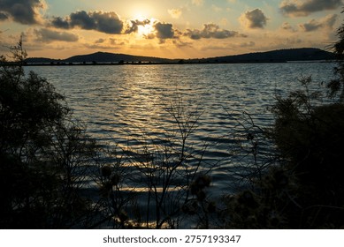 Dramatic sunset clouds over Gialova Lagoon wetland in Greece with reflections on calm water and distant hills.