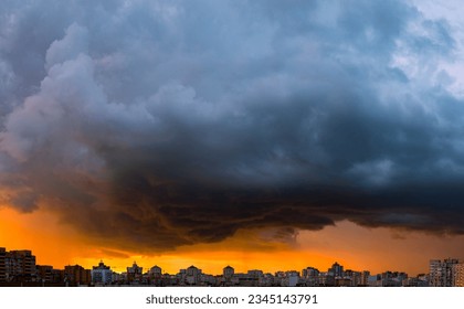 Dramatic sunset clouds over the modern city. Colorful stormy skies, urban panorama.