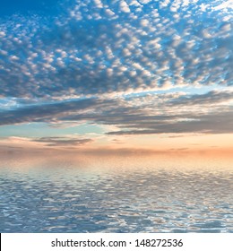 Dramatic sunset with clouds reflected in water. 