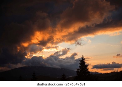 Dramatic sunset with dark clouds over a mountain landscape.