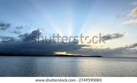 Dramatic sunset with distinctive sunbeams radiating from behind dark clouds