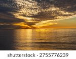 Dramatic sunset glow and colorful clouds over the Pacific Ocean at Sunset Cliffs, San Diego, with coastal cliffs and calm water creating a scenic background for travel and design use.