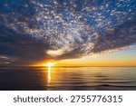 Dramatic sunset glow and colorful clouds over the Pacific Ocean at Sunset Cliffs, San Diego, with coastal cliffs and calm water creating a scenic background for travel and design use.