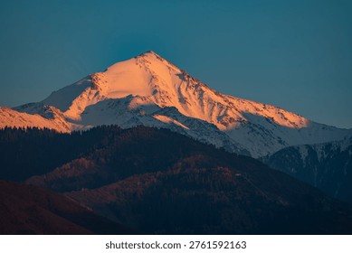 Dramatic Sunset Glow on High Altitude Mountain Top, Stunning Orange Light on Snow-Capped Peak at Dusk, Almaty, Kazakhstan, Central Asia, Satpayev peak, Soviet Peak