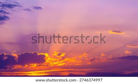 Dramatic sunset with intense gold and orange clouds, purple sky, and crepuscular sun rays spreading upward.