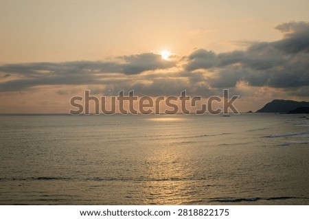 Dramatic sunset landscape over a tropical sea with crepuscular rays hitting the water surface.
