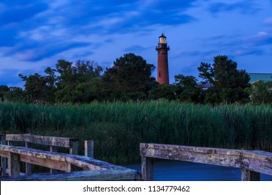 Dramatic sunset light and sky frame the Currituck lighthouse, its beacon shining, with foreground reeds and weathered boardwalk, Outer Banks, North Carolina, 2018.jpg