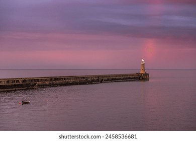 A dramatic sunset lights up the cloudy sky as a vibrant rainbow appears in Tynemouth in the North East of England