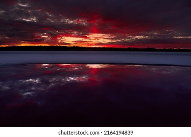 dramatic sunset in linkkumylly finland over a frozen lake - natural landscape photography