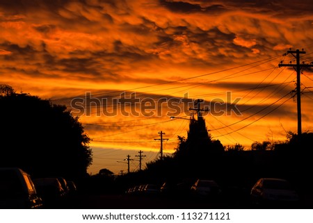 Dramatic sunset looking like a river of fire over an urban street with cars and streetlights