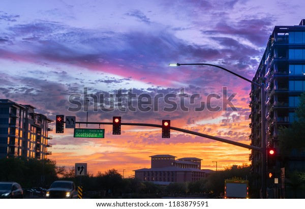 Dramatic sunset in North  Scottsdale,Arizona.  Cars\
drive by a busy intersection on Scottsdale rd and Kierland Blvd.\
Focus on road sign.