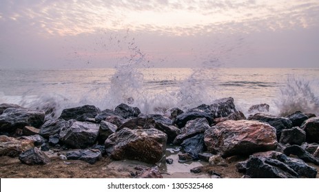 Dramatic sunset at the ocean with boulder rocks 