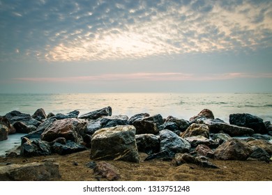 Dramatic sunset at the ocean with boulder rocks 