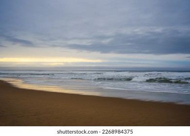 Dramatic sunset on the beach. Wide sandy beach, stormy sea, and beautiful cloudy sky, copy space for the text