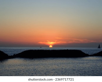 Dramatic Sunset on Magic Island Beach over the ocean with boats sailing on the water on Oahu, Hawaii. February 2015.