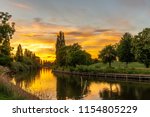 A dramatic sunset over a bend in the River Ouse in York.  A path runs alongside a tree-lined river bank.