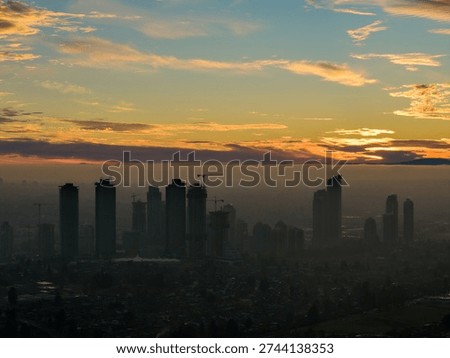 Dramatic sunset over Burnaby, BC, Canada’s urban skyline, cranes and silhouettes against a glowing horizon.