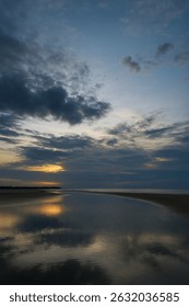 Dramatic sunset over a calm beach with reflective water, dark clouds, and a golden glow. Perfect for serene, moody, and atmospheric landscape shots. #SunsetBeach #CloudySky #CoastalBeauty
