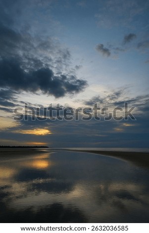 Dramatic sunset over a calm beach with reflective water, dark clouds, and a golden glow. Perfect for serene, moody, and atmospheric landscape shots. #SunsetBeach #CloudySky #CoastalBeauty
