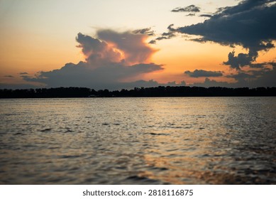 Dramatic sunset over calm lake with textured clouds.