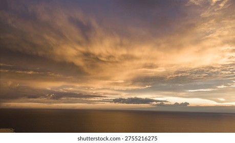Dramatic sunset over a calm ocean with vivid orange and purple clouds reflecting warm light on the water.
