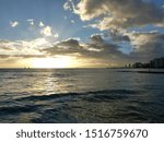Dramatic Sunset over the clouds and reflecting on the Pacific ocean on the water off the coast of Waikiki in Oahu, Hawaii with Waianae Mountain range visible.