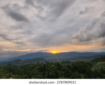 Dramatic sunset over mountain range with moody storm clouds, golden sun glowing behind blue hills and green forest landscape background

A breathtaking landscape capturing a dramatic golden sunset peeking through layers of dark, moody storm clouds over a distant blue mountain range and lush green forest. The striking contrast between the heavy sky and the warm glowing sun creates a powerful atmosphere of hope, tranquility, and natural beauty.