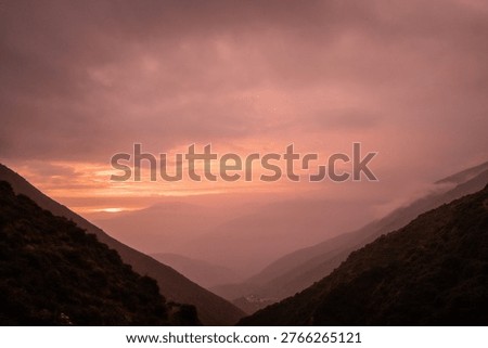 Dramatic Sunset Over Mountain Valley with Mist and Layers of Hil