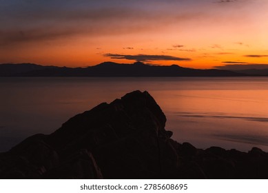 Dramatic sunset over the mountains and Great Salt Lake viewed from the rocky cliffs of Antelope Island State Park, Utah.