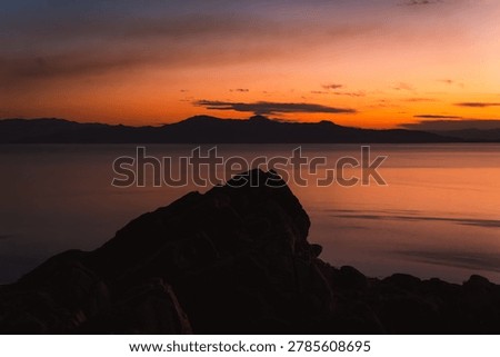 Dramatic sunset over the mountains and Great Salt Lake viewed from the rocky cliffs of Antelope Island State Park, Utah.