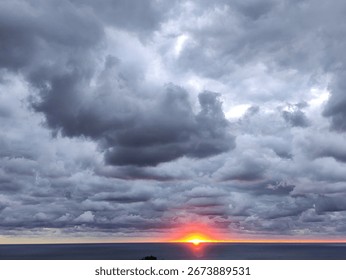 Dramatic sunset over the ocean with dark clouds and vibrant colors at twilight
