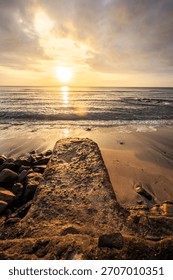 Dramatic Sunset Over the Ocean with Foreground Rock Structure