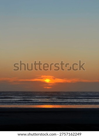 Dramatic sunset over ocean horizon with sun peering through clouds.