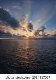 Dramatic Sunset Over the Ocean with Sun Rays Breaking Through Clouds