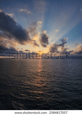 Dramatic Sunset Over the Ocean with Sun Rays Breaking Through Clouds