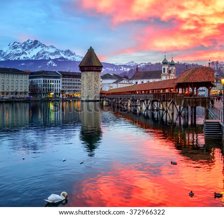 Dramatic sunset over the old town of Lucerne, Chapel Bridge, Water tower and snow covered Pilatus Mountain, Switzerland