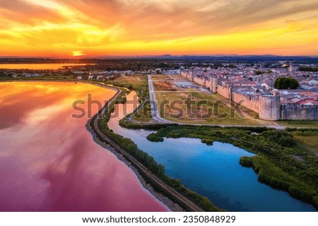 Dramatic sunset over the pink salt lakes and the medieval walled Old town of Aigues-Mortes, Camargue, France