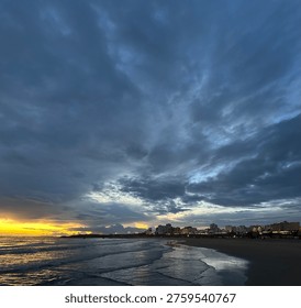 Dramatic sunset over Praia da Rocha Beach under cloudy sky in the coastal city Portimão, Faro, Portugal, February 2025