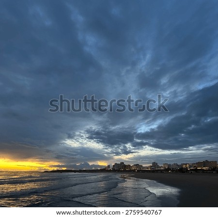 Dramatic sunset over Praia da Rocha Beach under cloudy sky in the coastal city Portimão, Faro, Portugal, February 2025