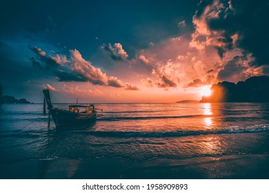 Dramatic sunset over Railay Beach at Krabi, Thailand, with traditional longtail boat in the foreground.