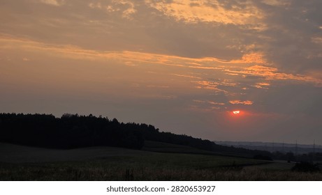 Dramatic sunset over rural fields and rolling hills